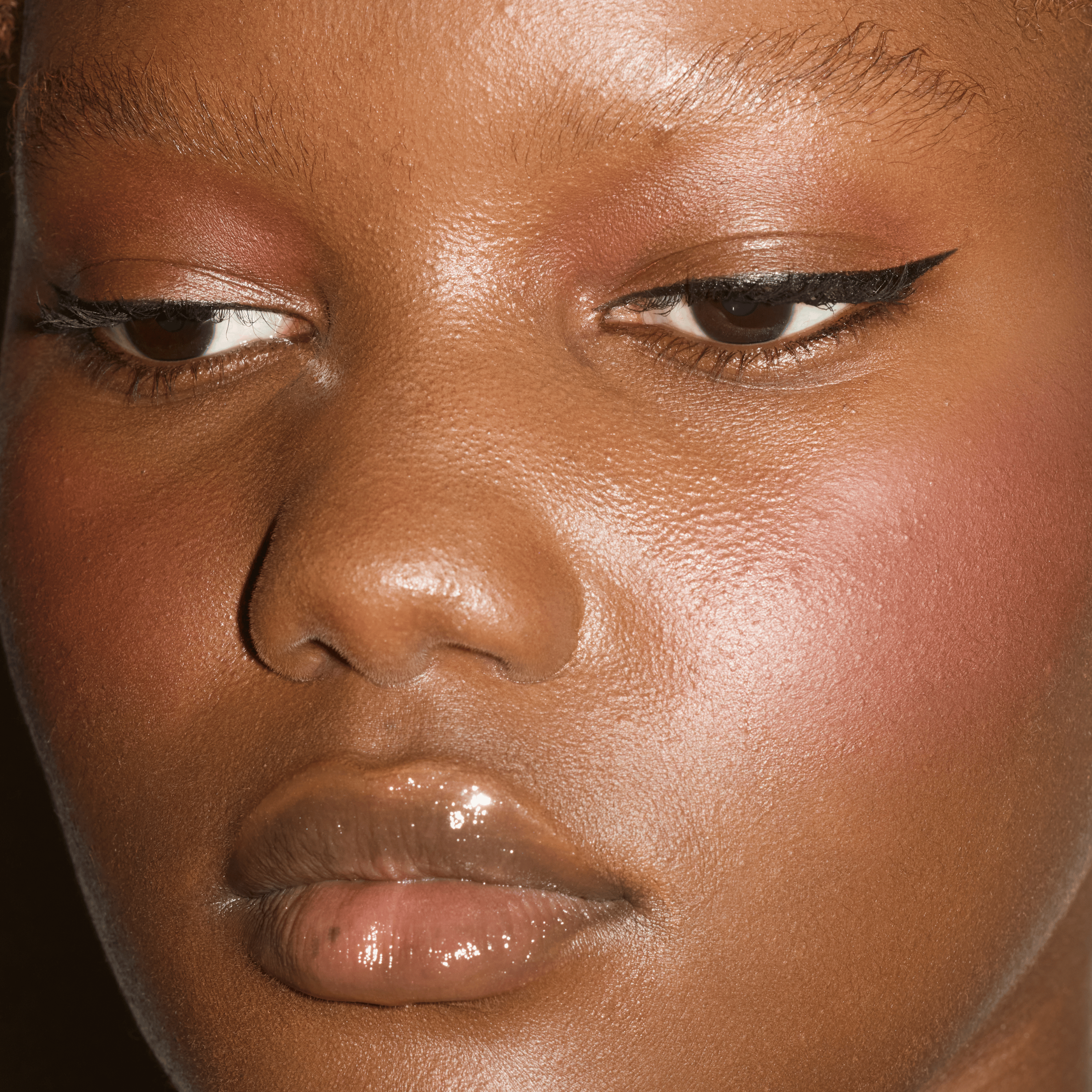 Close-up of sharp black winged eyeliner paired with softly glowing skin and glossy lips.
