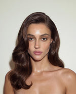 Model with polished side-swept waves and glossy, controlled hair, styled with SOPHIA MAE Hairspray for a smooth, refined finish.