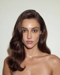 Model with polished side-swept waves and glossy, controlled hair, styled with SOPHIA MAE Hairspray for a smooth, refined finish.