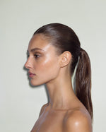 Side-profile portrait of a model with a sleek, high-shine ponytail, showcasing the smooth, polished hold of SOPHIA MAE Hairspray.