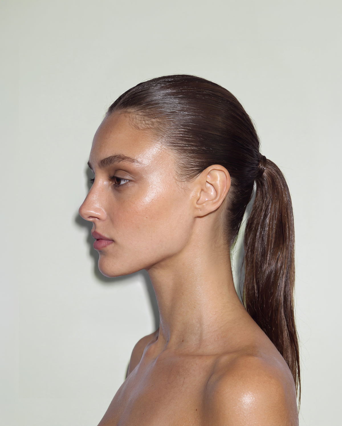 Side-profile portrait of a model with a sleek, high-shine ponytail, showcasing the smooth, polished hold of SOPHIA MAE Hairspray.