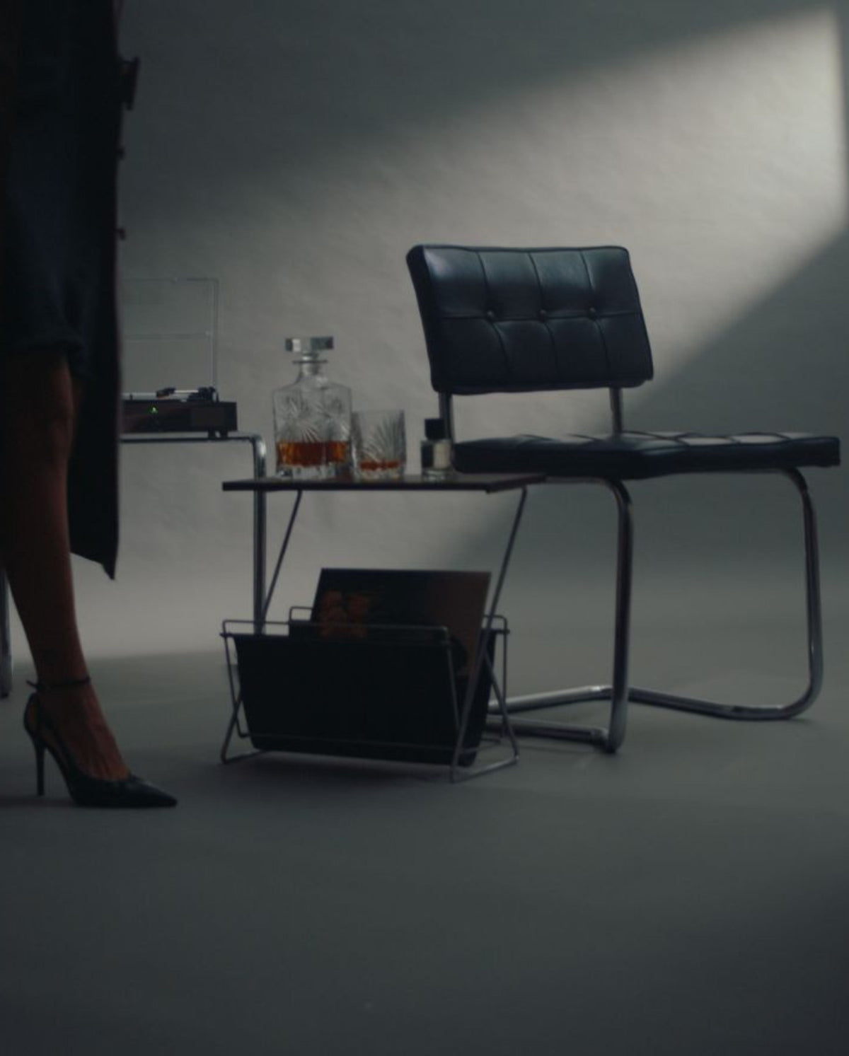 A minimal interior with a black leather chair, record player and Without Saying Much eau de parfum from SOPHIA MAE. 