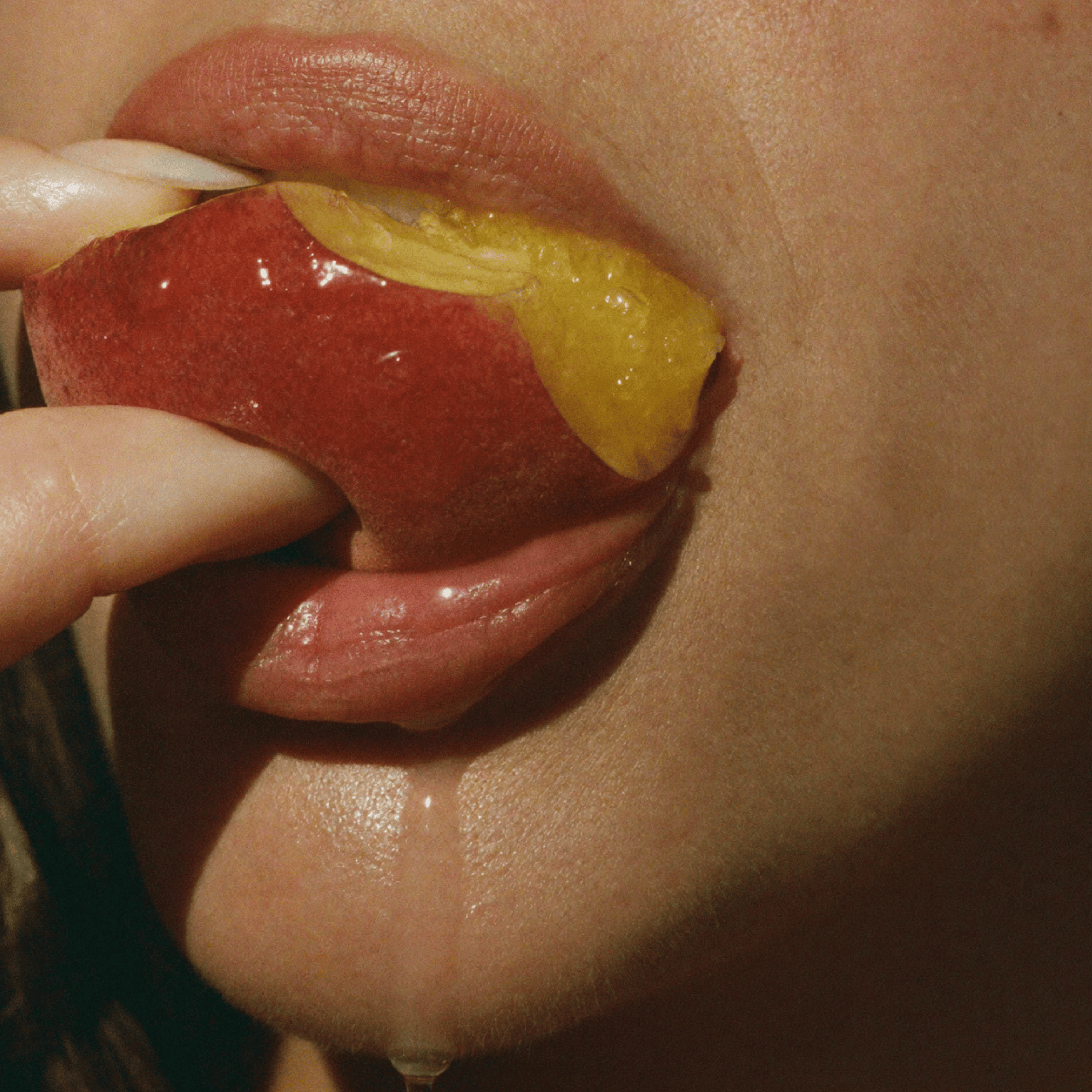Close-up of glossy lips biting into a ripe peach, lifestyle image for SOPHIA MAE Soft Summer Kiss eau de parfum.