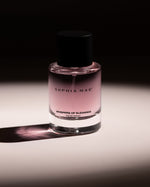 SOPHIA MAE Whispers of Elegance eau de parfum bottle with soft pink fragrance against a dark, elegant background.