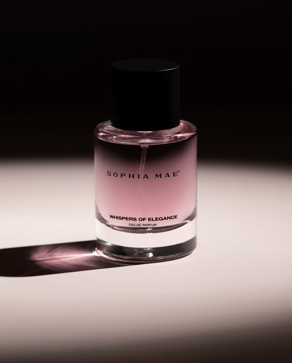SOPHIA MAE Whispers of Elegance eau de parfum bottle with soft pink fragrance against a dark, elegant background.