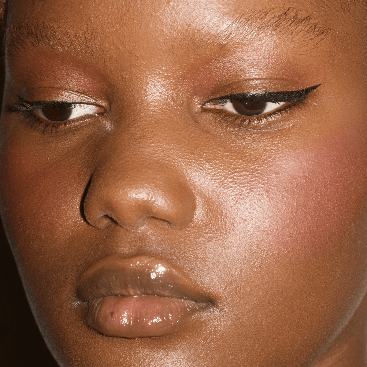 Close-up of sharp black winged eyeliner paired with softly glowing skin and glossy lips.