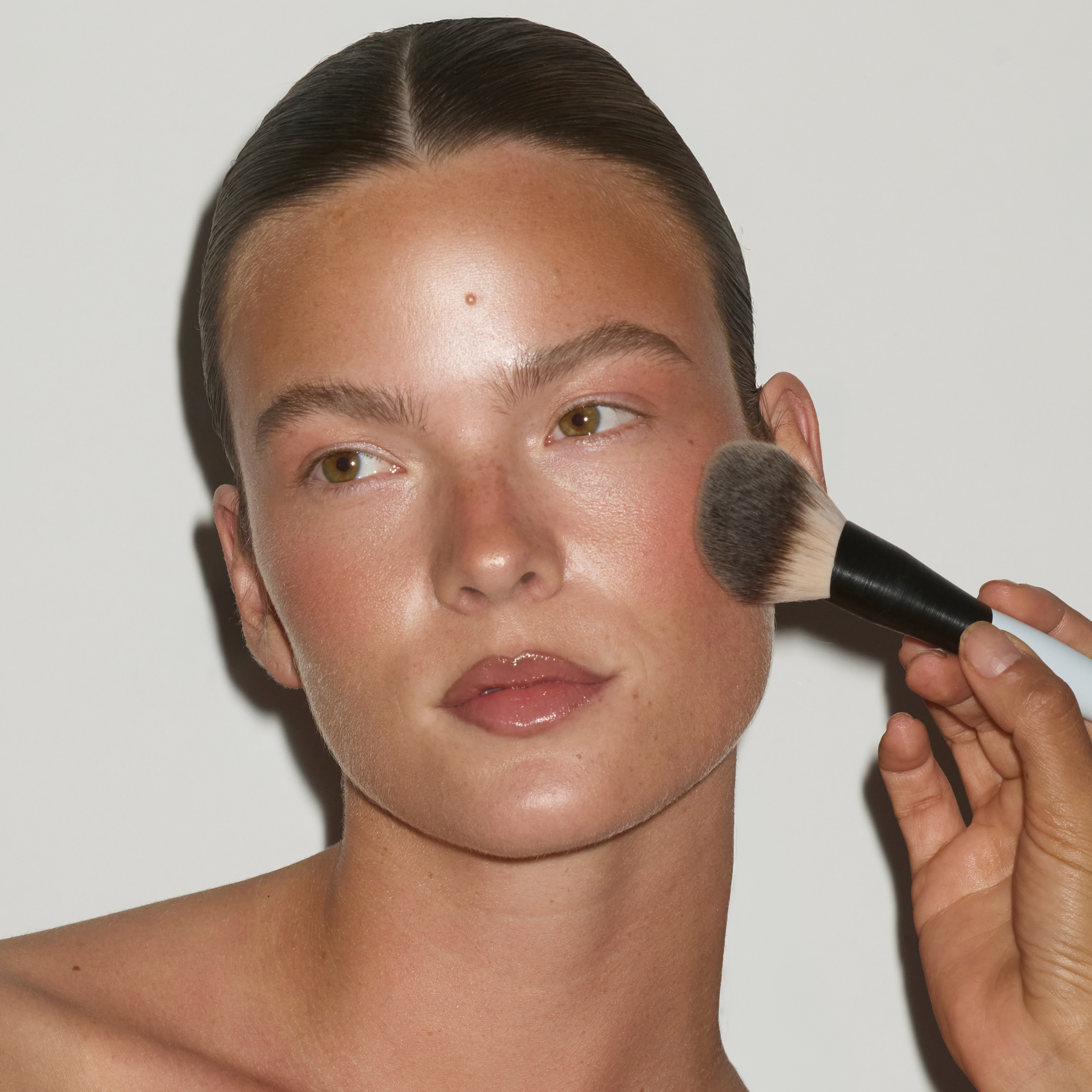 SOPHIA MAE Matte Bronzer being applied to the cheek with a large makeup brush.