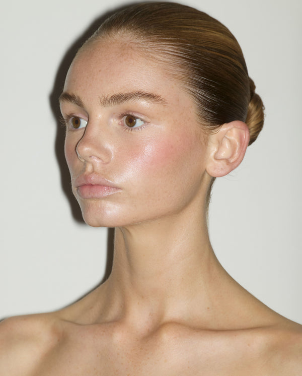 Model with slicked-back hair wearing SOPHIA MAE Skin Tint, showing a luminous complexion with soft blush and natural-looking skin texture.