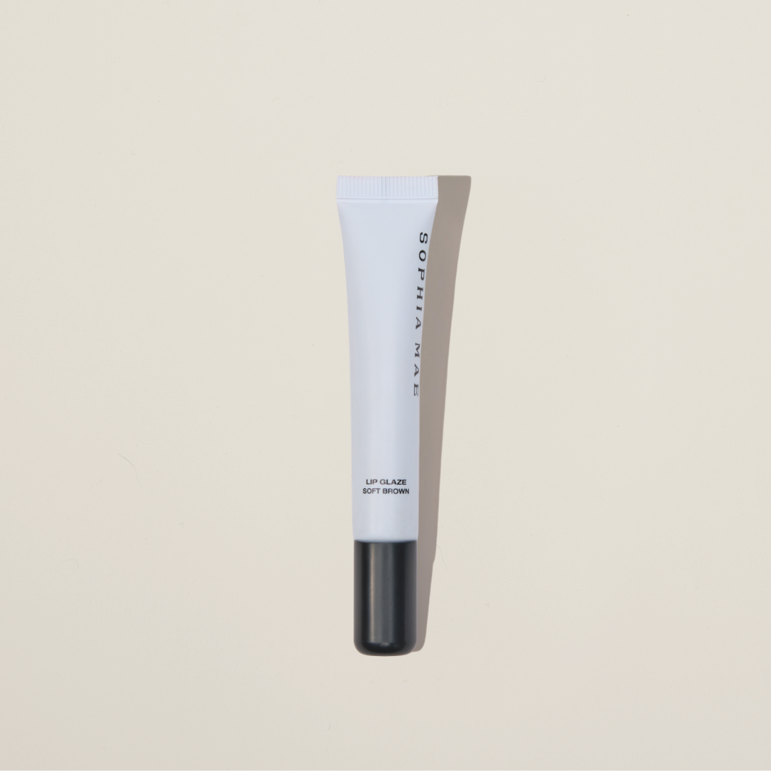 SOPHIA MAE Lip Glaze in Soft Brown with beige background. 