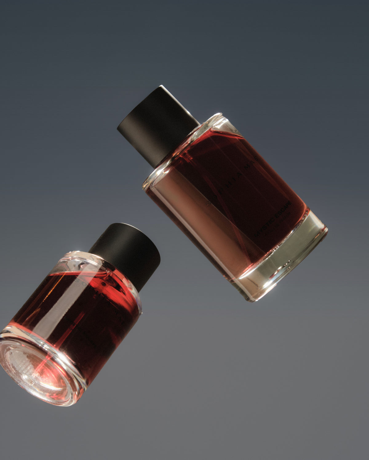 Two SOPHIA MAE Mystic Escape eau de parfum bottles floating against a dark grey background.