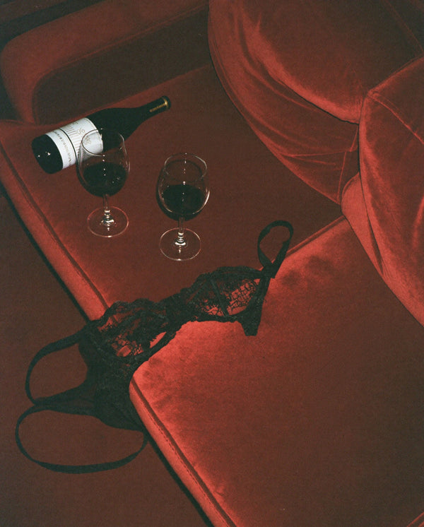 Mystic Escape Eau de Parfum by SOPHIA MAE with red velvet, black lace lingerie and wine glasses in a sensual setting.