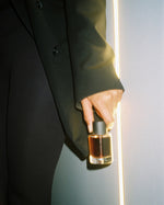 SOPHIA MAE Mystic Escape Eau de Parfum held in hand, illuminated by warm golden light.