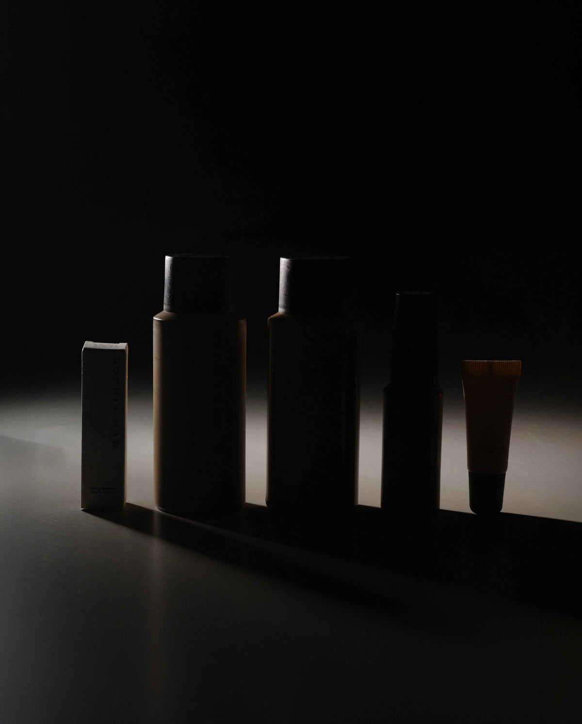 Silhouettes of the five SOPHIA MAE Bestseller selection products, including mini haircare, tanning mist, lip balm and For a Reason perfume.