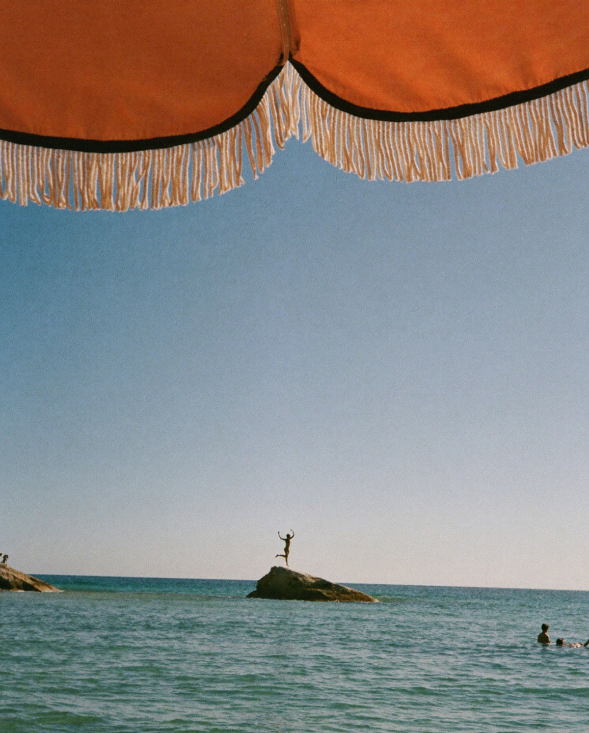 Ocean view beneath a striped parasol, capturing the sun-soaked mood of Golden Mirage perfume by SOPHIA MAE.