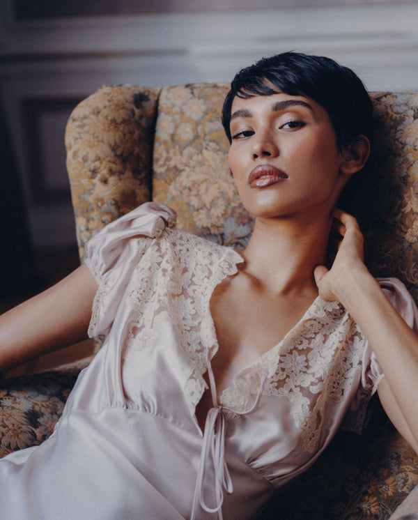 Model reclining in a vintage floral armchair, capturing the romantic mood of SOPHIA MAE Still in Bloom.