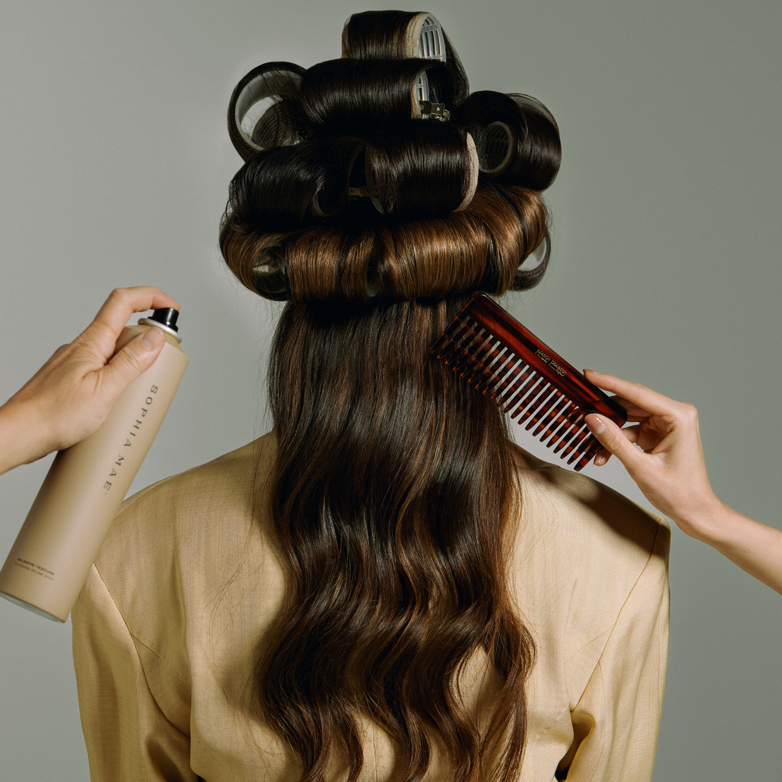 SOPHIA MAE Volumizing Texture Spray applied while styling long hair with rollers.