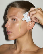 Close-up of a model applying SOPHIA MAE Skin Tint to her cheek, showing its lightweight texture and natural, dewy glow.
