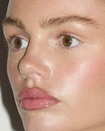 Close-up beauty portrait featuring SOPHIA MAE Lip Glaze on softly glossy lips, paired with luminous skin and a fresh, natural flush.