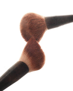 Close-up of two SOPHIA MAE Powder Brushes with soft, dense bristles coated in bronzing powder.