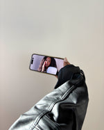 Hand holding a smartphone showing a beauty model, styled for SOPHIA MAE Cream Blush.