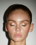 Model wearing SOPHIA MAE Eyeshadow Palette with eyes closed, showcasing a luminous rose-gold shimmer blended with soft warm brown tones.