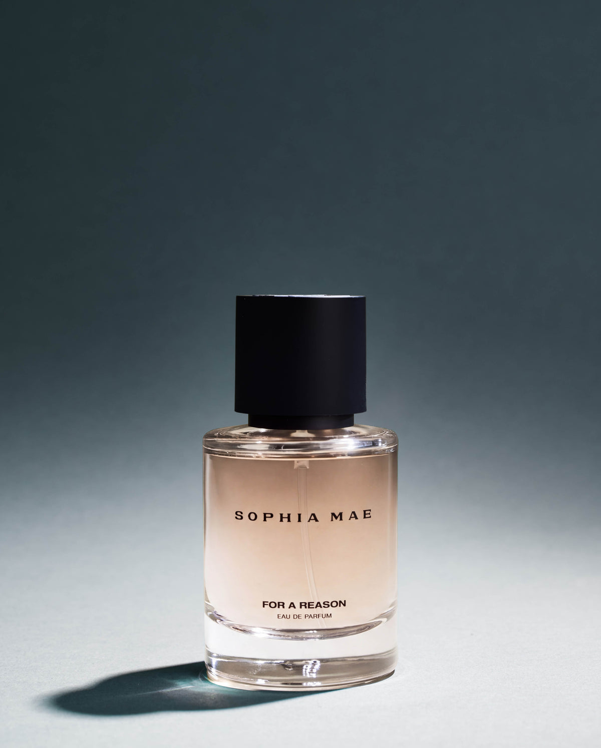 SOPHIA MAE For A Reason Eau de Parfum bottle photographed in moody studio lighting, with soft shadows that reflect the fragrance’s warm, mysterious character.