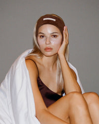 Model wearing a brown SOPHIA MAE headband during her skincare routine.