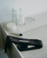 Brown SOPHIA MAE headband styled with skincare products on a bathroom counter.