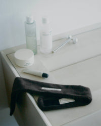 Brown SOPHIA MAE headband styled with skincare products on a bathroom counter.