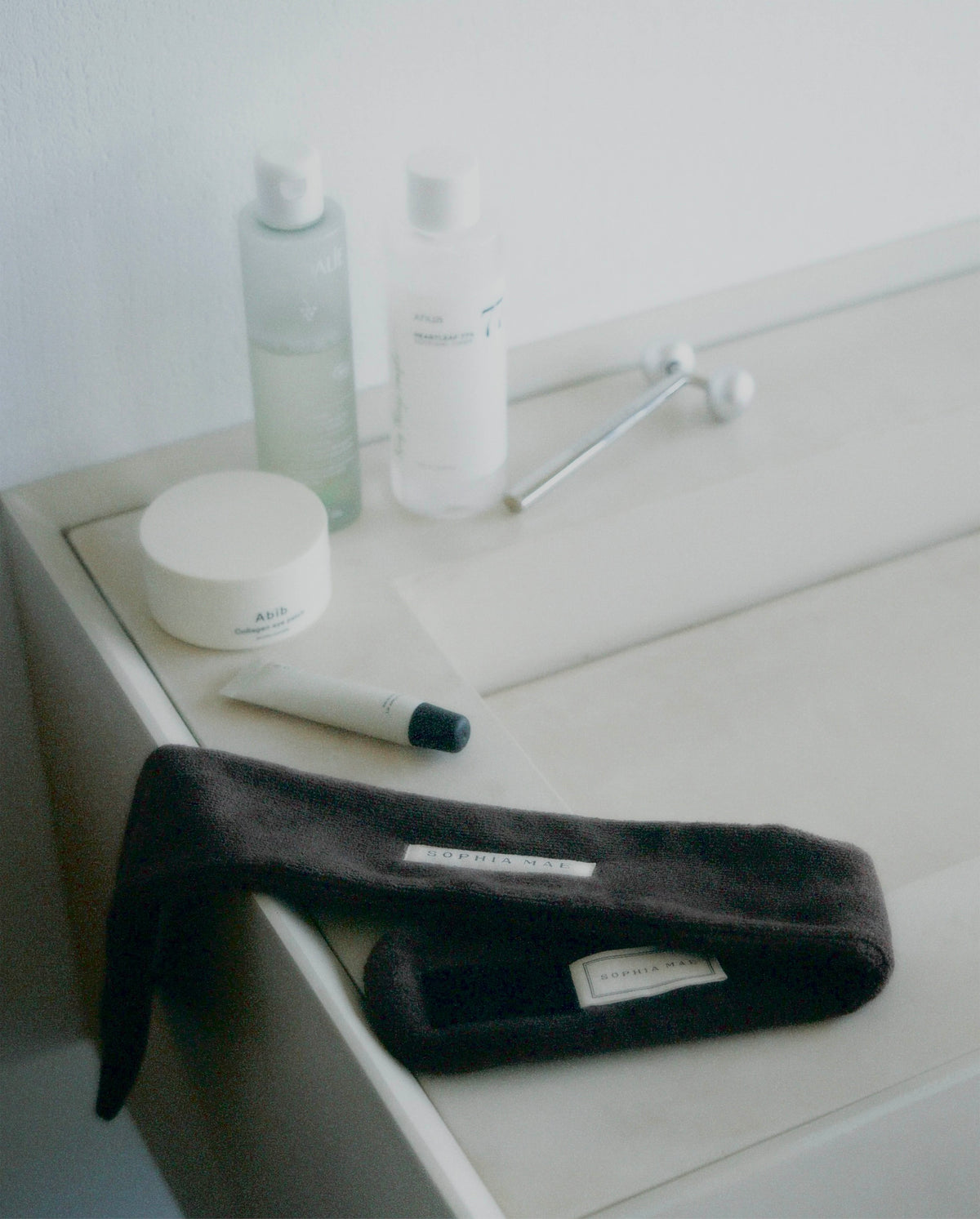 Brown SOPHIA MAE headband styled with skincare products on a bathroom counter.
