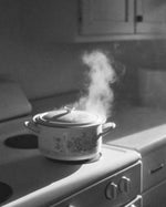 Black-and-white kitchen scene for SOPHIA MAE Kept For A While, with steam rising from a vintage floral cooking pot on the stove.