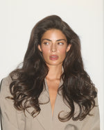 Model with voluminous, glossy waves and soft glam makeup, showcasing a polished SOPHIA MAE hair look with full-bodied movement and shine.
