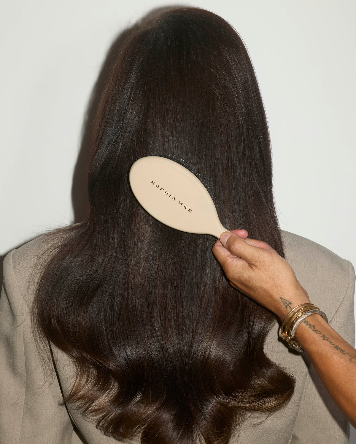 Back view of long, glossy hair being brushed with the SOPHIA MAE Hairbrush, showing a smooth, polished finish with soft movement.