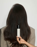 SOPHIA MAE Hair Perfume held in front of long, glossy dark hair.