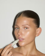 Model applying SOPHIA MAE Liquid Lip Balm to her lips.