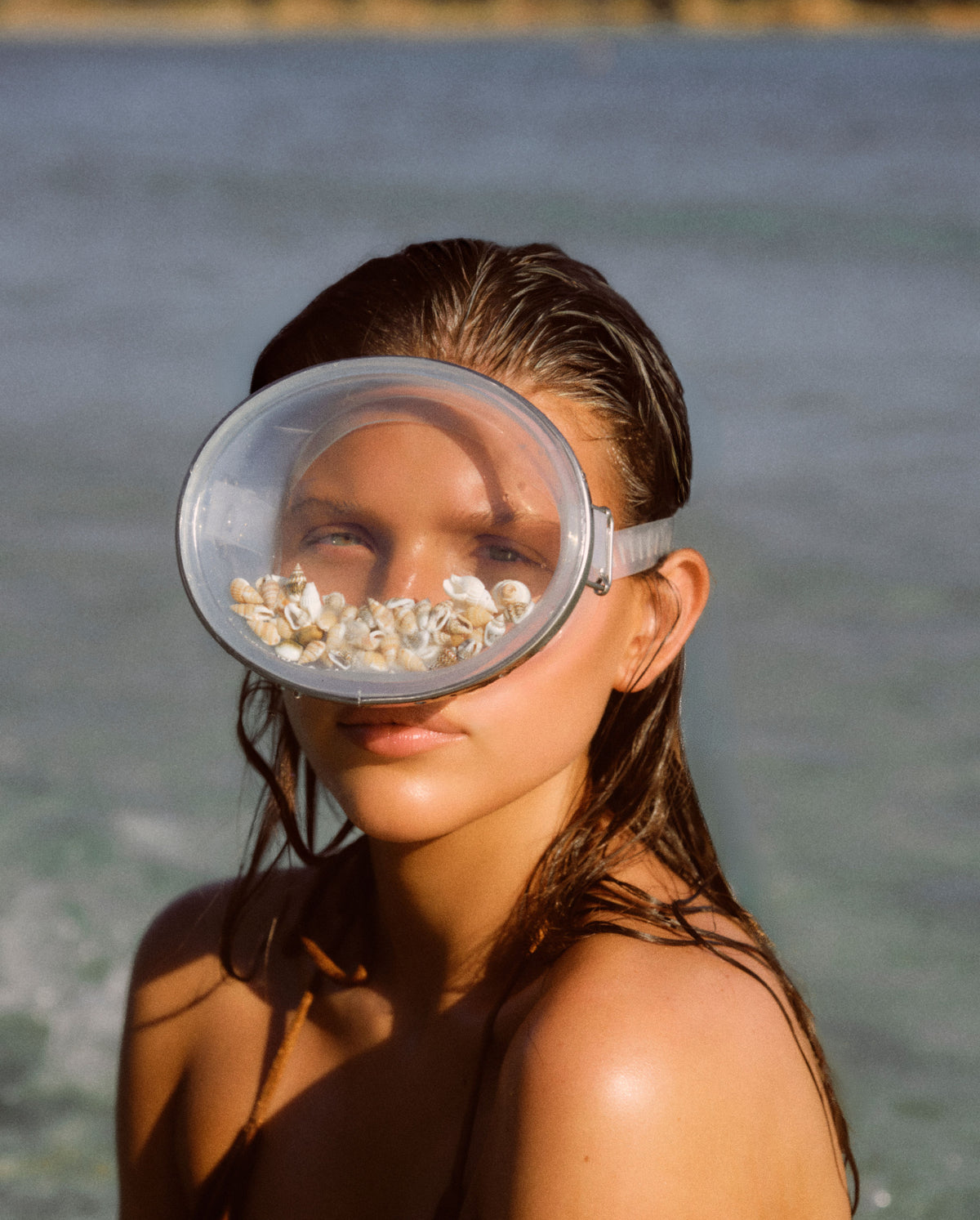 Model by the sea wearing a shell-filled snorkel mask, capturing the coastal mood of SOPHIA MAE Written in Sand eau de parfum.