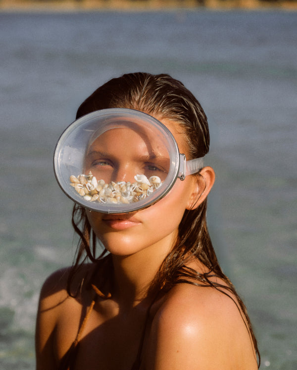 Model by the sea wearing a shell-filled snorkel mask, capturing the coastal mood of SOPHIA MAE Written in Sand eau de parfum.