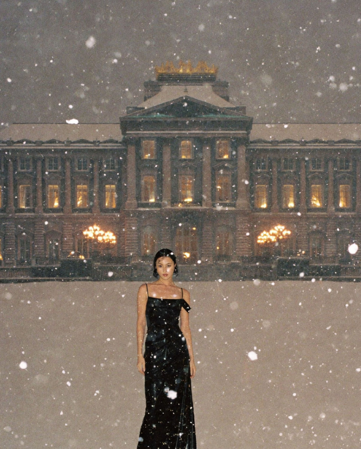 Model in a black dress standing in falling snow for SOPHIA MAE Arctic Spice perfume.