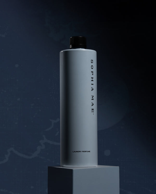 SOPHIA MAE Midnight Melody Laundry Perfume bottle on a pedestal against a dark midnight blue background.