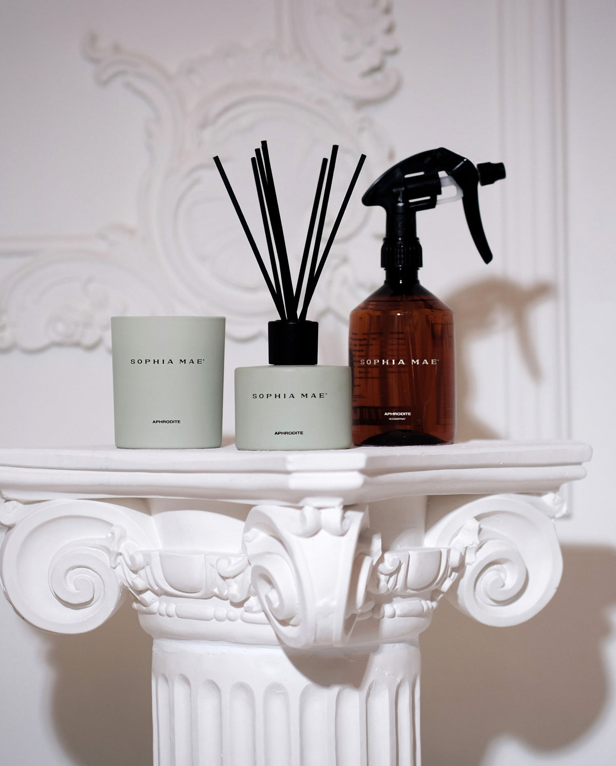 SOPHIA MAE Aphrodite Midi Scented Candle in a soft sage green jar, styled alongside the matching reed diffuser on an ornate white mantel.