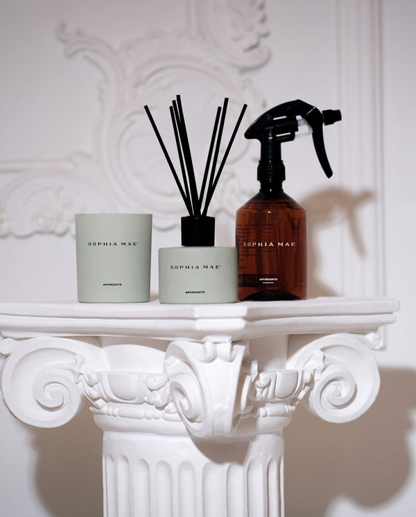 SOPHIA MAE Aphrodite Midi Scented Candle in a soft sage green jar, styled alongside the matching reed diffuser on an ornate white mantel.
