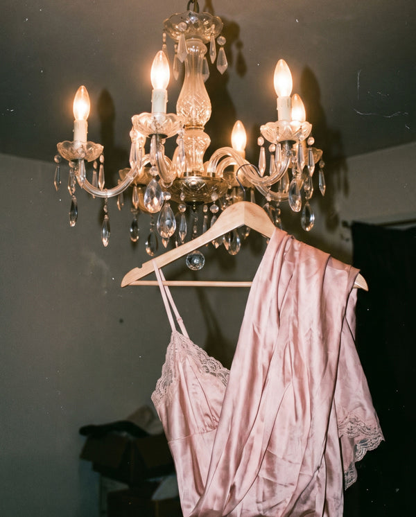 A pink silk dress hanging from the ceiling light, displaying the mood of Whispers of Elegance eau de parfum SOPHIA MAE