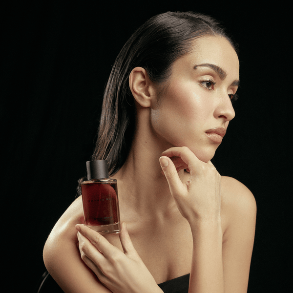 Model holding SOPHIA MAE Mystic Escape eau de parfum against a black studio background.