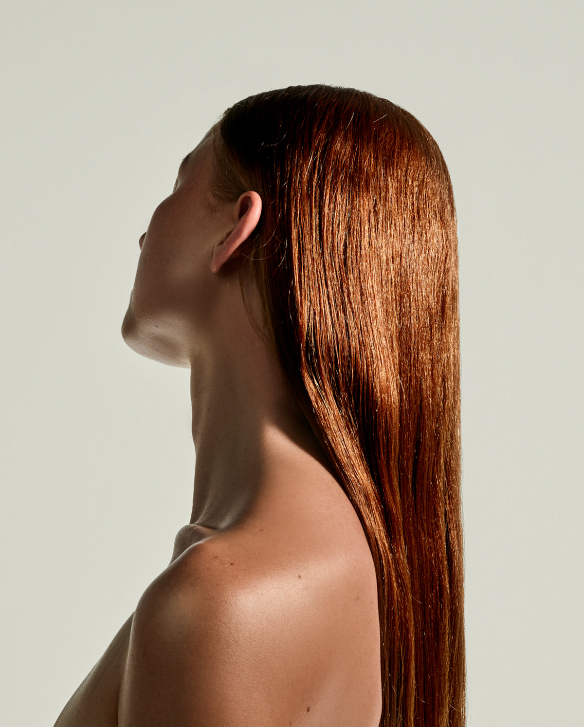 Side profile of a model with sleek, glossy hair showing the shine of SOPHIA MAE Nourishing Body & Hair Elixir.