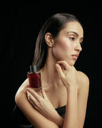 Model holding SOPHIA MAE Mystic Escape eau de parfum against a black studio background.