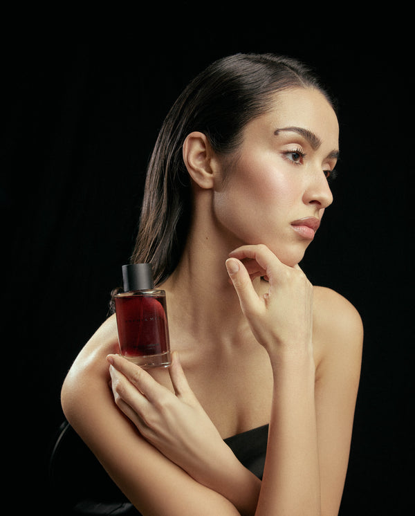 Model holding SOPHIA MAE Mystic Escape eau de parfum against a black studio background.