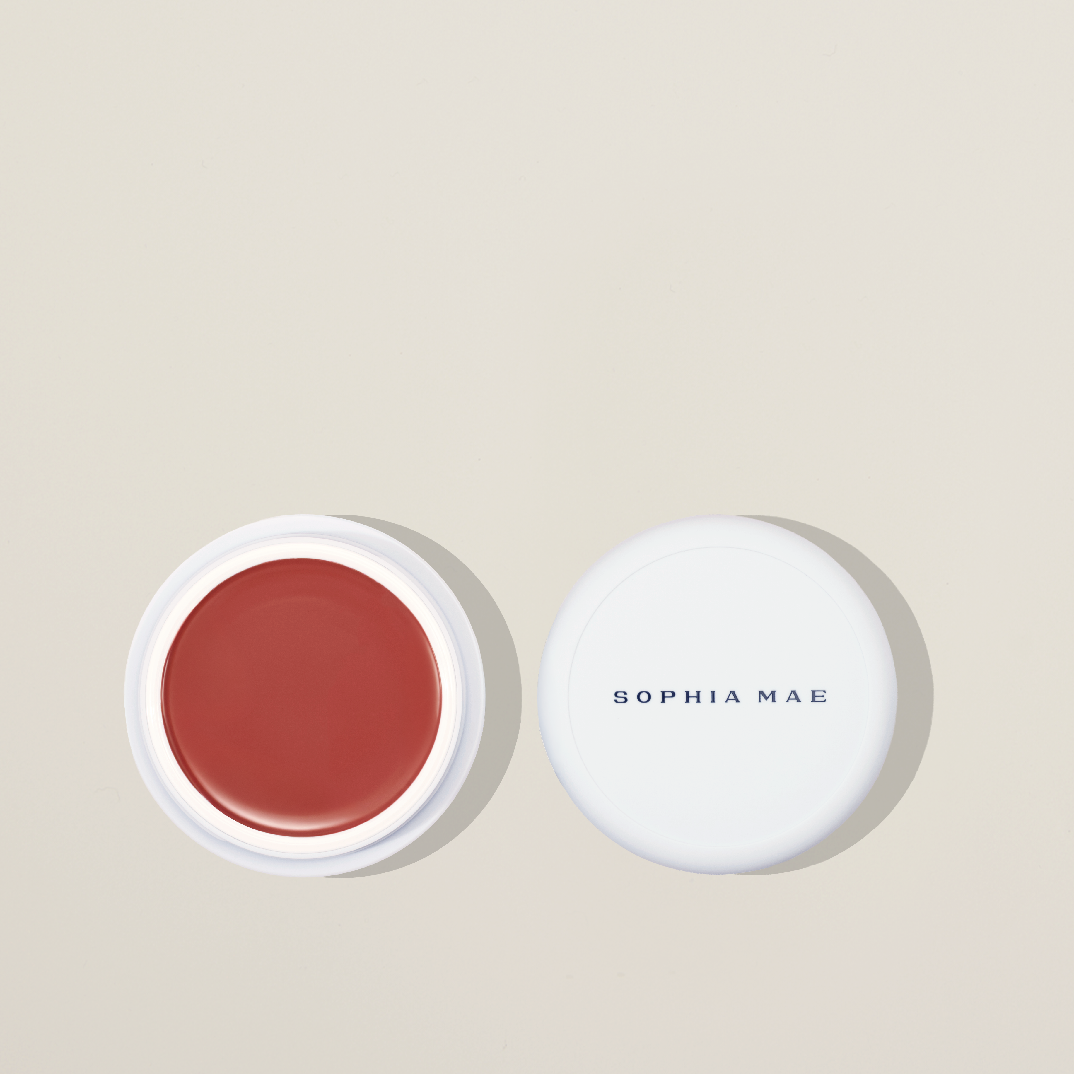 SOPHIA MAE Tan Blusher: creamy, sun-kissed cream blush for a golden-hour glow with hydrating castor and sweet almond oils. Tan blush on beige background.