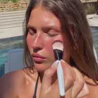 Model blending pink blush across her cheeks and nose with the SOPHIA MAE Liquid Blending Brush.