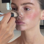 SOPHIA MAE Powder Brush picking up Matte Bronzer and blending it across a model’s face and neck.